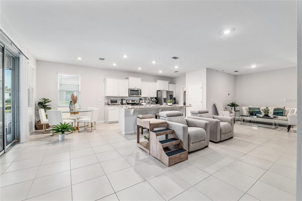 6243 Southwest 89th St Road Ocala, FL 34476 - Photo 39 of 57 a living room with lots of white furniture and a dining table with kitchen view
