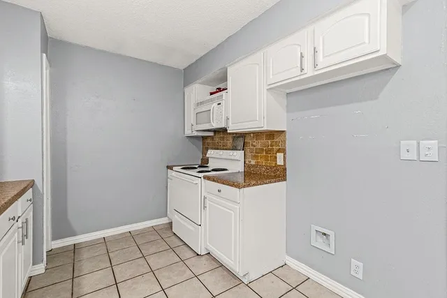 a kitchen with granite countertop white cabinets and white appliances