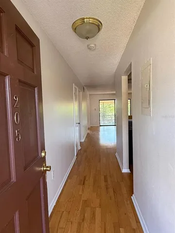 a view of a hallway with wooden floor and chandelier