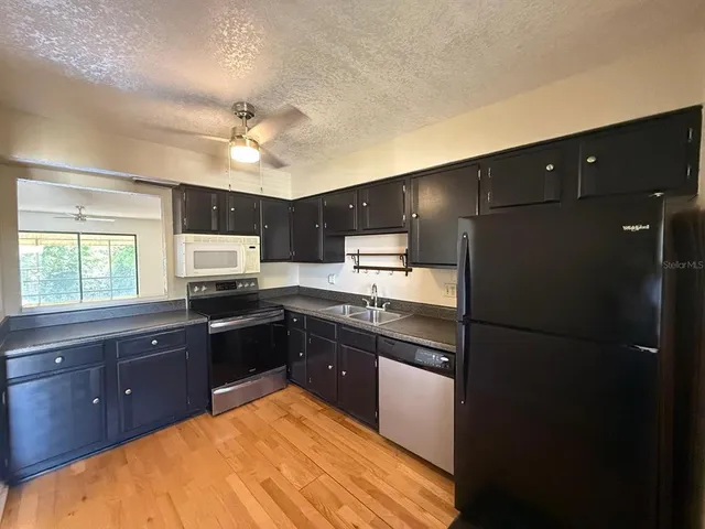 a kitchen with stainless steel appliances granite countertop a refrigerator a sink dishwasher a stove and a refrigerator