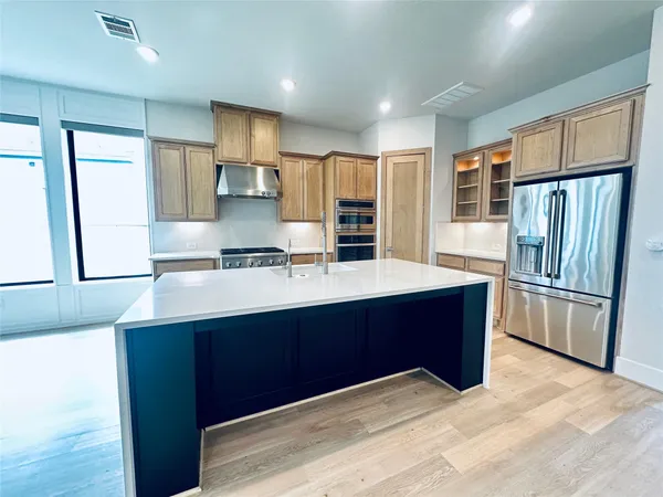 a kitchen with stainless steel appliances a refrigerator and a stove top oven