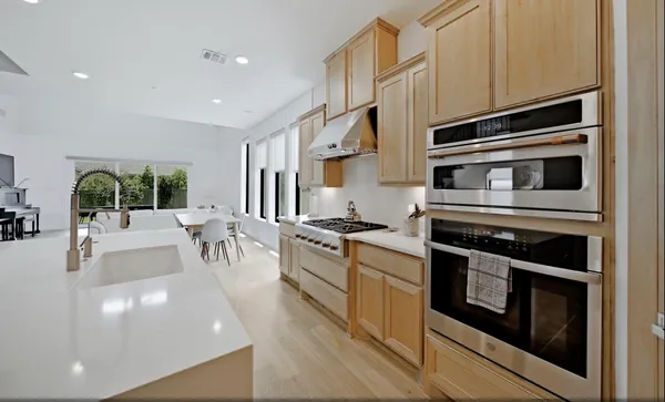 a kitchen with stainless steel appliances kitchen island granite countertop a stove a sink and white cabinets