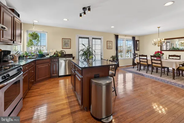 a living room with stainless steel appliances granite countertop furniture wooden floor and a kitchen view