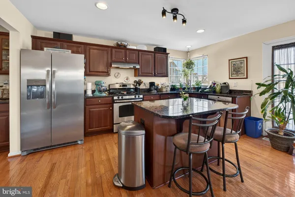 a kitchen with granite countertop a table chairs stainless steel appliances and wooden floor
