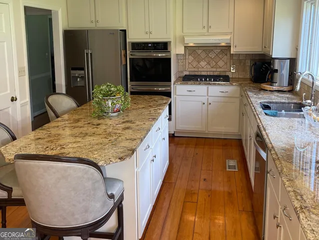 a kitchen with kitchen island a counter top space cabinets and stainless steel appliances