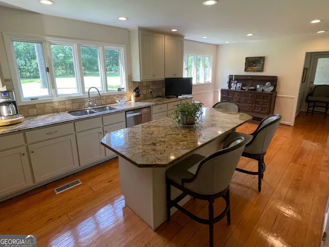 a kitchen with granite countertop kitchen island stainless steel appliances a table and chairs in it