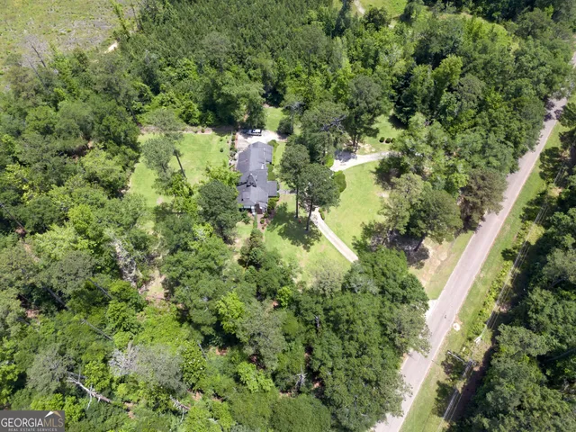 an aerial view of residential house with outdoor space and trees all around