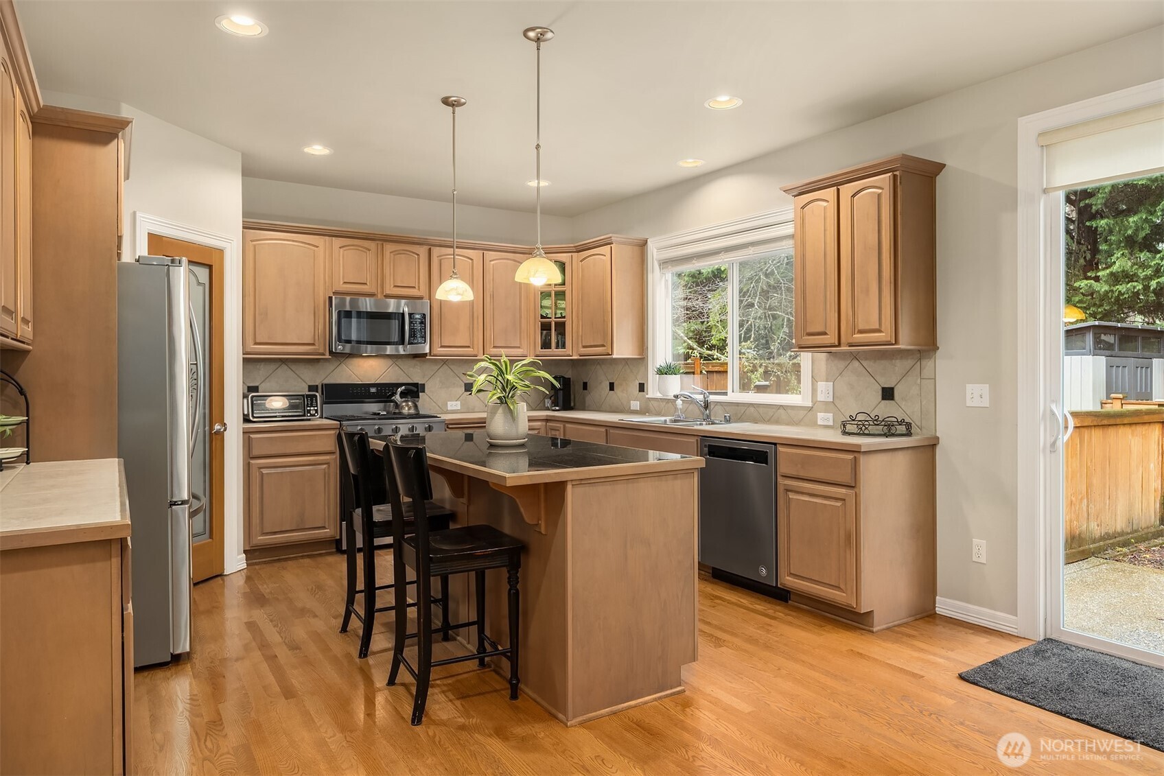 23703 Southeast 284th Street Maple Valley, WA 98038 - Photo 9 of 33 a kitchen with kitchen island granite countertop a sink cabinets and stainless steel appliances