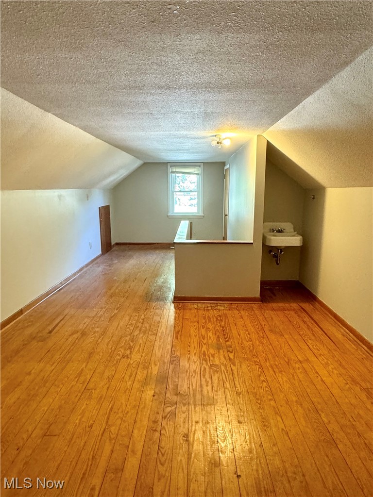 1655 Spring Street Coshocton, OH 43812 - Photo 19 of 19 Bonus room featuring light hardwood / wood-style floors, sink, a textured ceiling, and vaulted ceiling