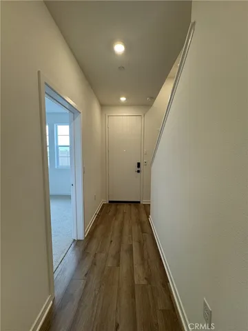 a view of an empty room with wooden floor and window