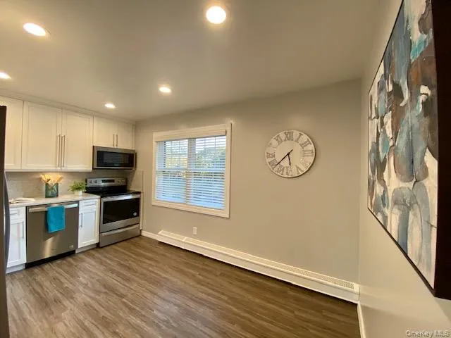 a view of a kitchen with a sink dishwasher wooden floor and a window
