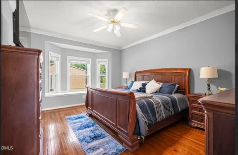 a bedroom with a bed lamp and a large window with wooden floor