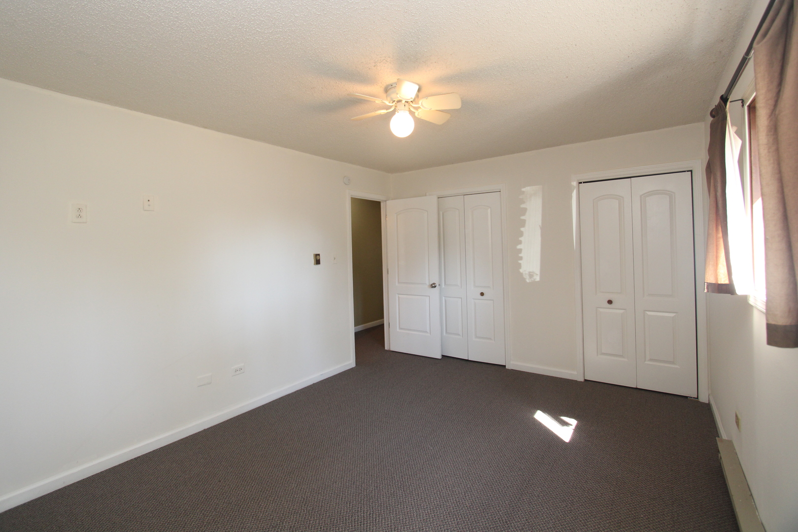 212 Madison Street, Unit 1B Joliet, IL 60435 - Photo 12 of 21 an empty room with a chandelier fan and windows