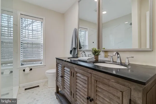 a bathroom with a granite countertop sink a toilet and a mirror