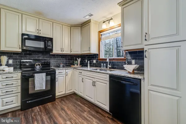 a kitchen with stainless steel appliances granite countertop a stove a sink and white cabinets