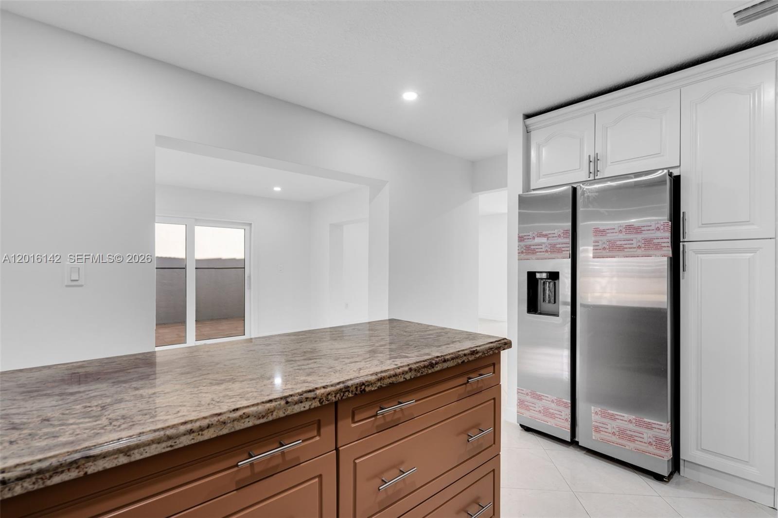 14755 Southwest 82nd Terrace Miami, FL 33193 - Photo 12 of 32 a kitchen with granite countertop a refrigerator and wooden cabinets