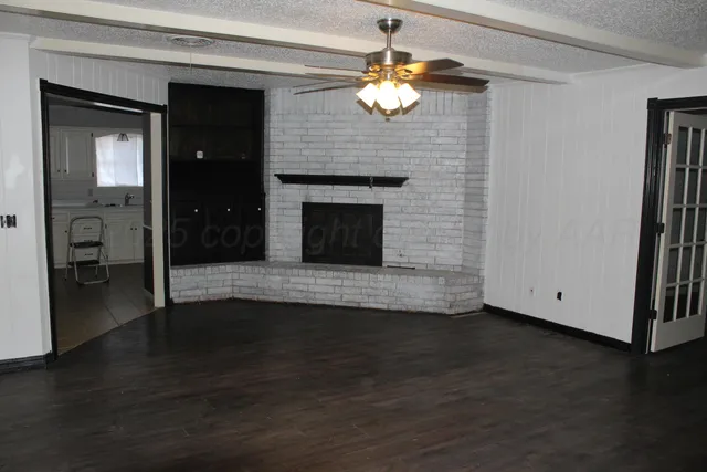 an empty room with wooden floor mirror and windows