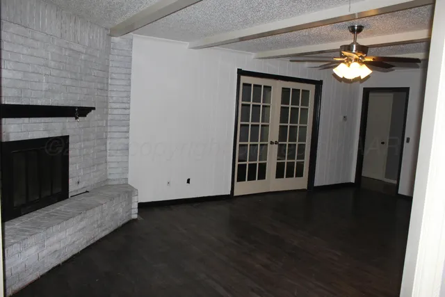 a view of an empty room with wooden floor and a fireplace