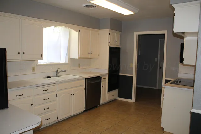 a kitchen with white cabinets and refrigerator
