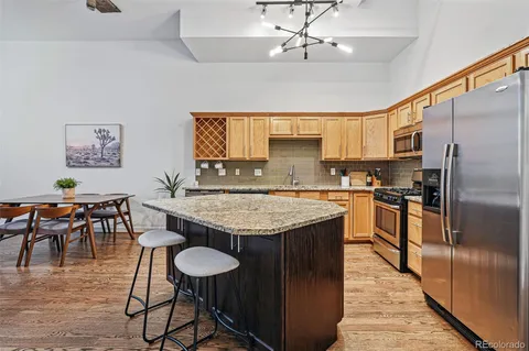 a kitchen with stainless steel appliances granite countertop table chairs sink and stove