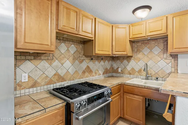 a kitchen with granite countertop a sink stove and cabinets