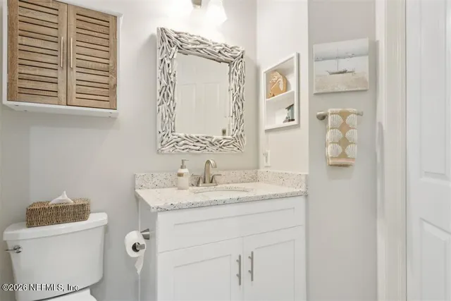 a bathroom with a granite countertop sink toilet and mirror