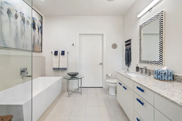 a bathroom with a granite countertop double vanity sink a mirror and a bathtub
