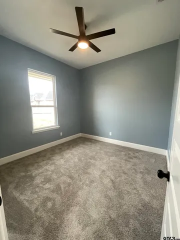 an empty room with a window and a fan