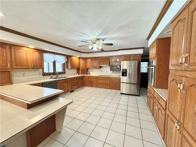 a kitchen with stainless steel appliances kitchen island granite countertop a refrigerator and a stove top oven