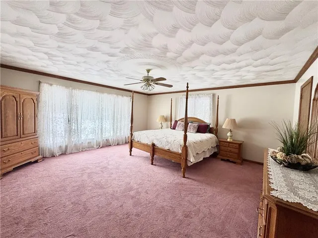 a spacious bedroom with a bed table flowerpot and window