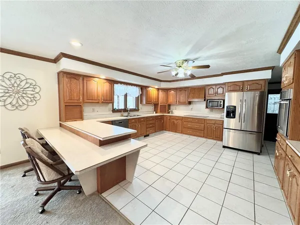 a kitchen with stainless steel appliances kitchen island granite countertop a sink a stove a refrigerator a microwave oven with white cabinets and wooden floor