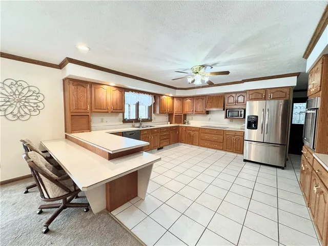 a kitchen with stainless steel appliances kitchen island granite countertop a sink a stove a refrigerator a microwave oven with white cabinets and wooden floor