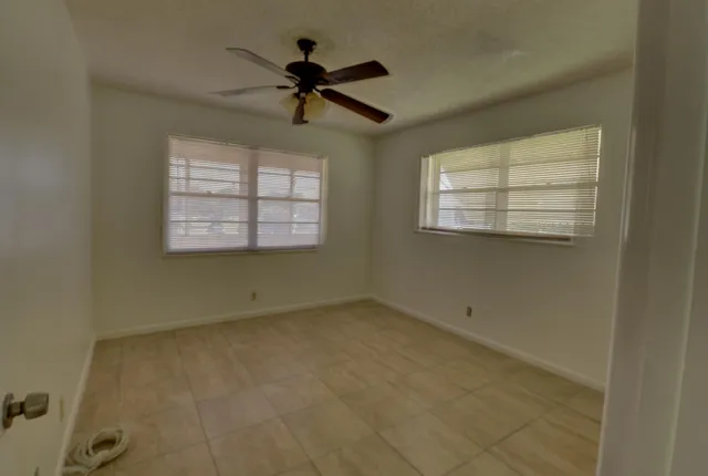 an empty room with windows and fan