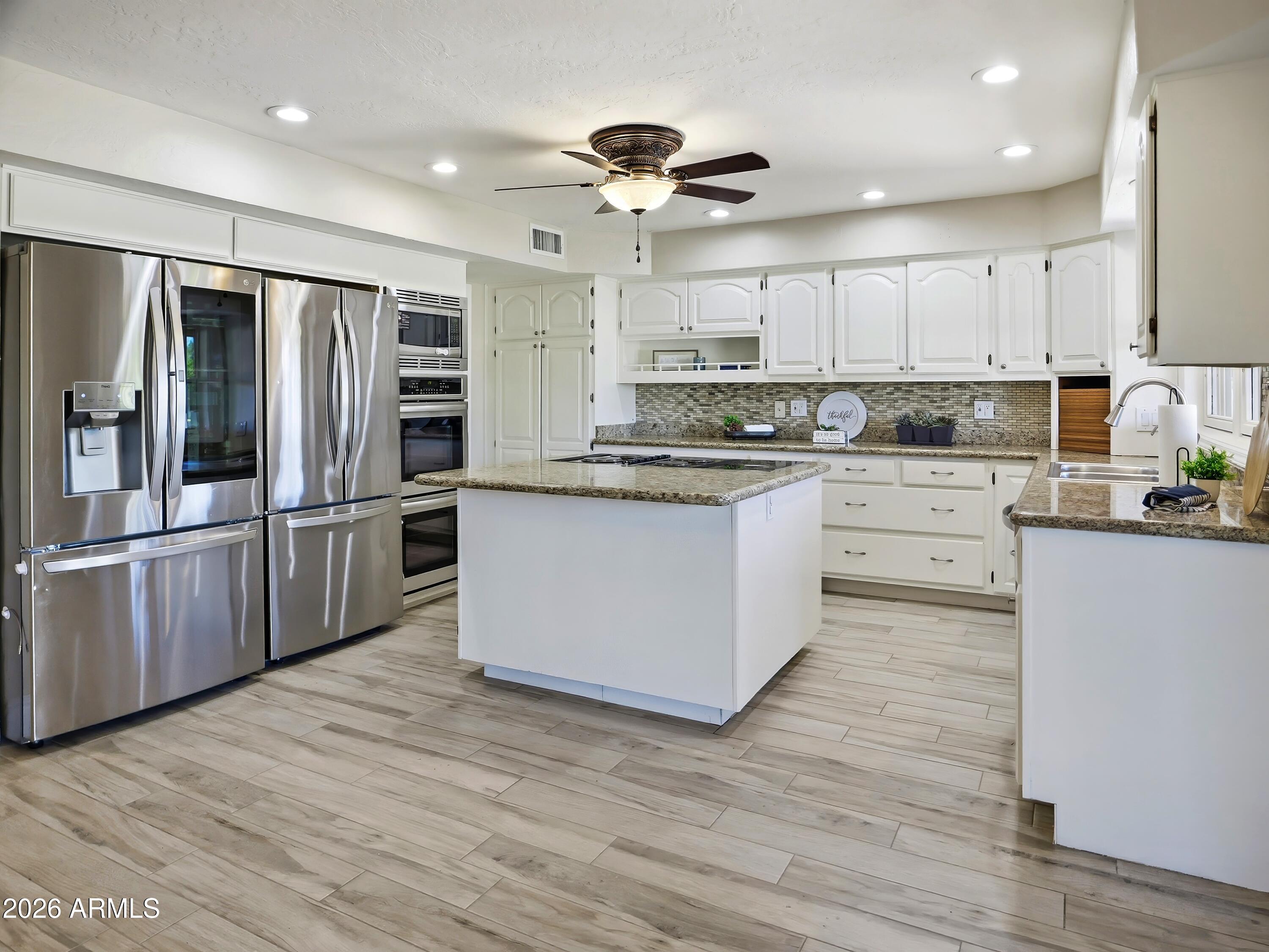 3154 East Inverness Avenue Mesa, AZ 85204 - Photo 12 of 70 a kitchen with stainless steel appliances granite countertop a refrigerator a stove top oven a sink and dishwasher with wooden floor