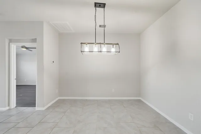 a view of a room with a hanging light and kitchen view