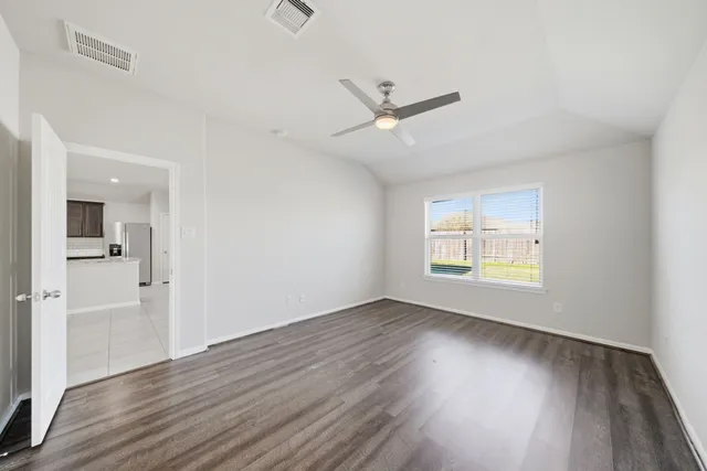 a view of an empty room with wooden floor and a window