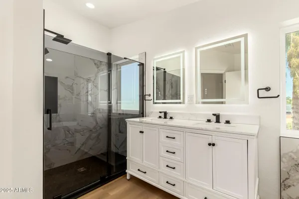 a bathroom with a double vanity sink mirror and shower