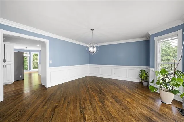 a view of an empty room with wooden floor and a potted plant