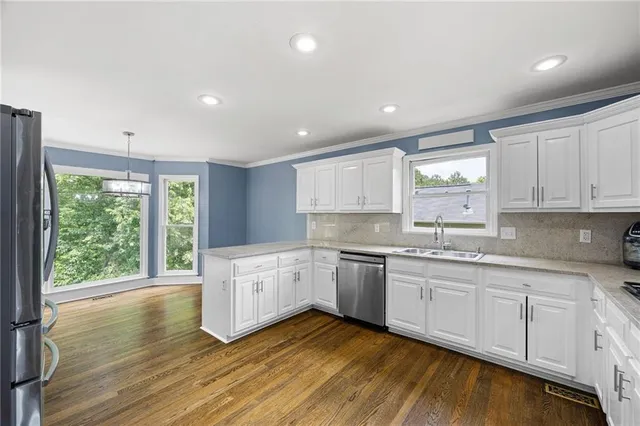 a large kitchen with a lot of white cabinets and wooden floor
