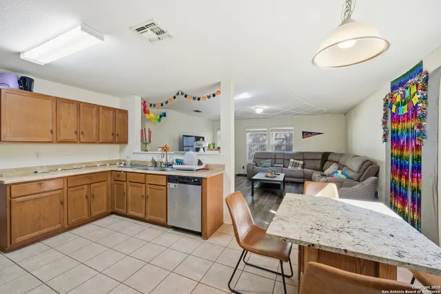 a kitchen with stainless steel appliances granite countertop a sink dishwasher a stove a dining table and chairs with wooden floor