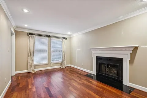an empty room with wooden floor fireplace and windows