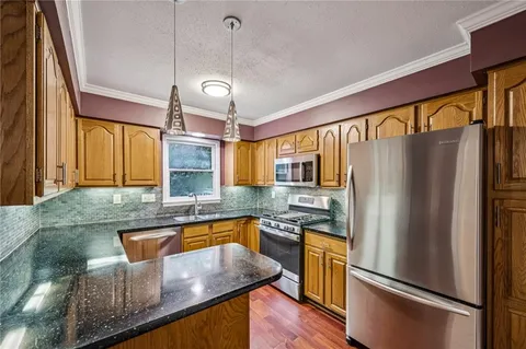a kitchen with stainless steel appliances granite countertop a refrigerator a stove and a sink with wooden floor
