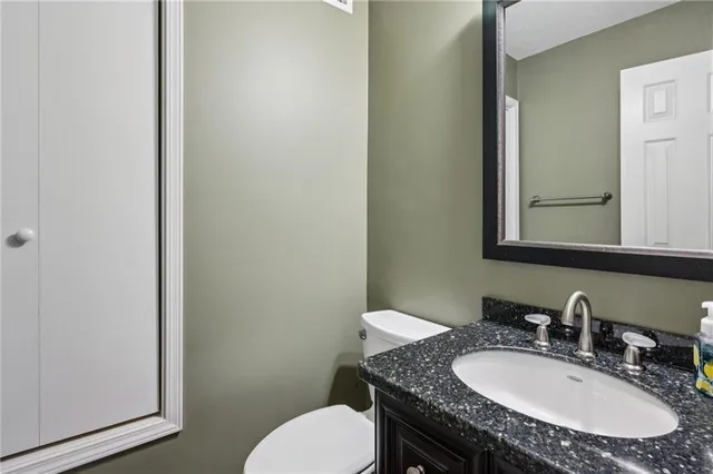 a bathroom with a granite countertop toilet a sink and a mirror
