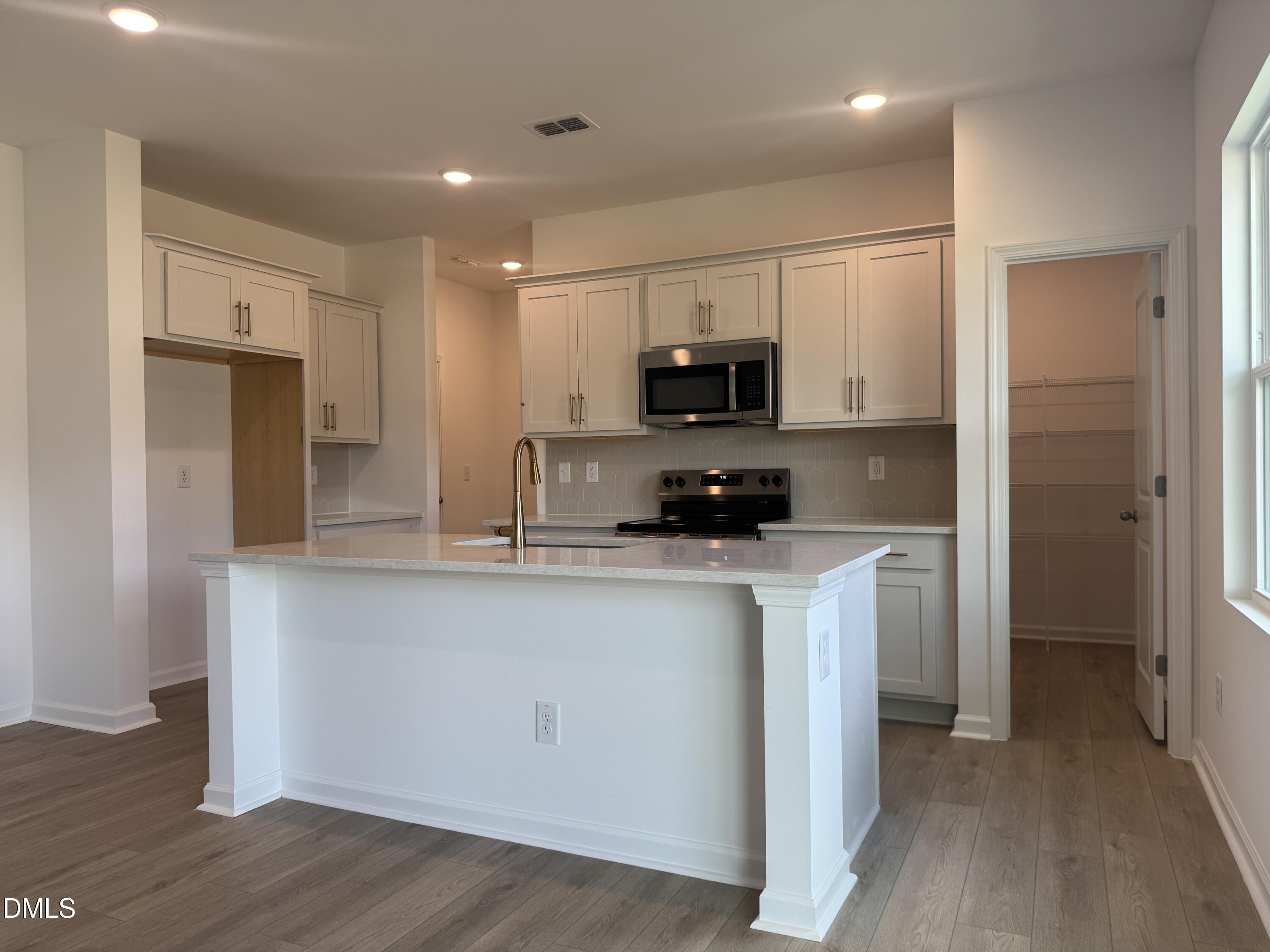 11742 Salers Loop Middlesex, NC 27557 - Photo 3 of 20 a kitchen with stainless steel appliances a refrigerator a sink and white cabinets