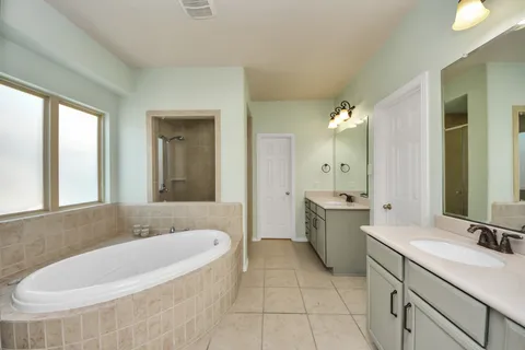 a spacious bathroom with a bathtub sink and mirror