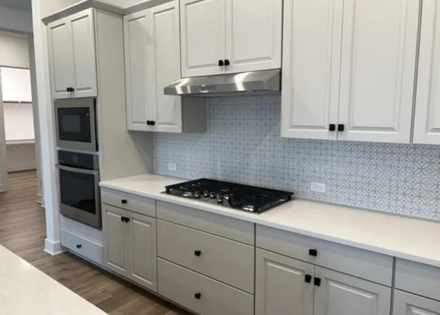 a kitchen with white cabinets and appliances