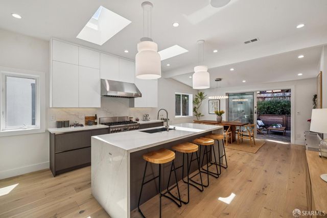 a kitchen with stainless steel appliances granite countertop a stove a sink a kitchen island with chairs and wooden floor