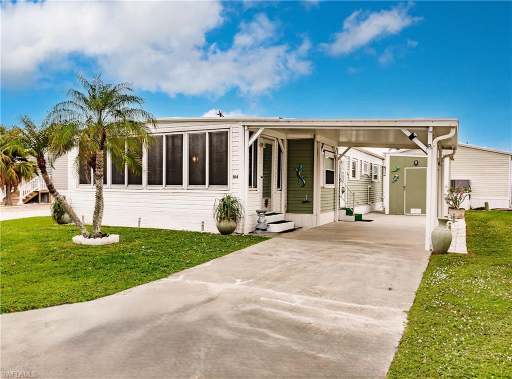 Front with a carport, lo0ng driveway, shed and a front lawn