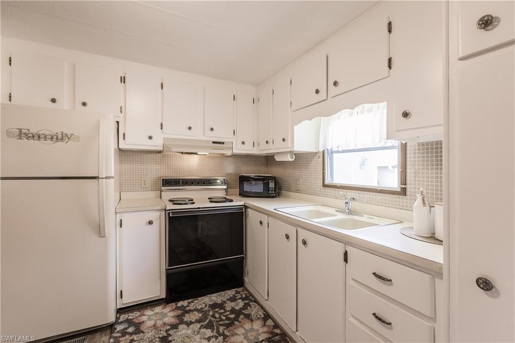 10100 Burnt Store Road, Unit 104 Punta Gorda, FL 33950 - Photo 11 of 46 Kitchen featuring tasteful backsplash, white cabinetry, sink, and white appliances