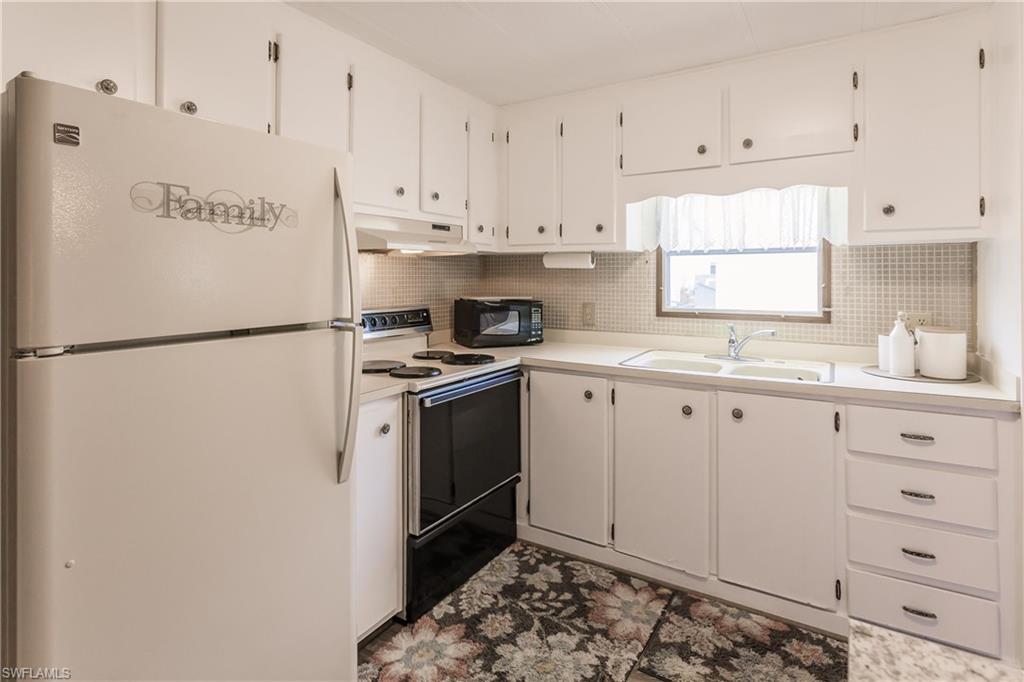 10100 Burnt Store Road, Unit 104 Punta Gorda, FL 33950 - Photo 12 of 46 Kitchen featuring white cabinets, white appliances, backsplash, and sink